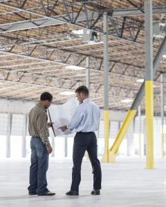 Architect and contractor reviewing architectural drawings for an existing commercial warehouse building renovation project