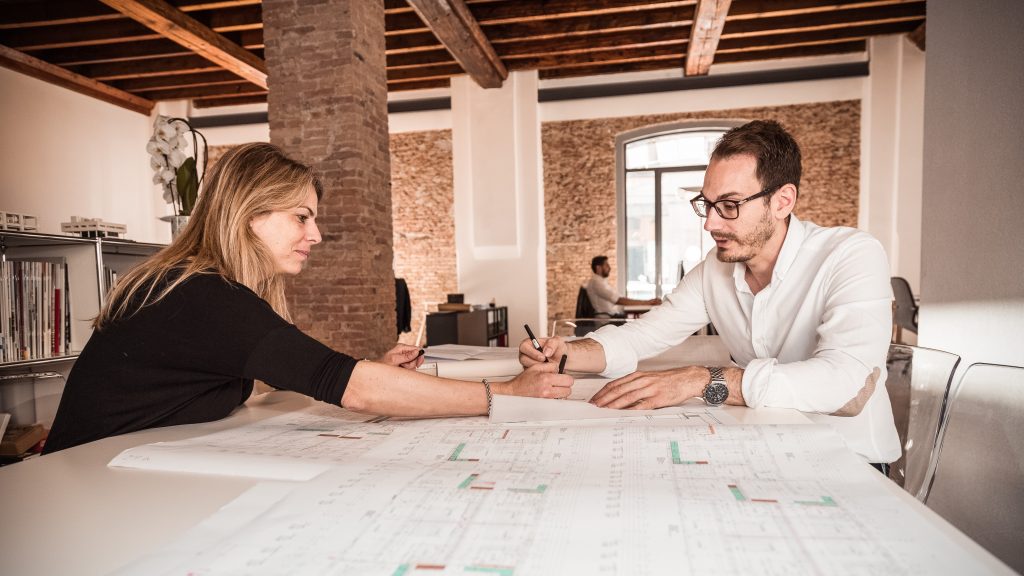 Architect and owner reviewing a commercial renovation project with a practical early-stage planning approach in an office setting